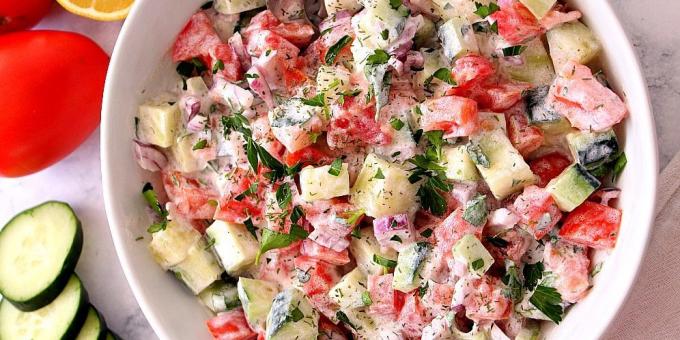 Salade de concombres et de tomates avec des oignons et la vinaigrette à la crème sure