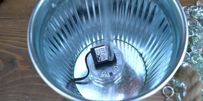 Comment faire une fontaine à faire soi-même: mettre un tube et une lampe dans un seau